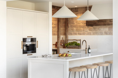 Immagine di una cucina stile rurale con ante in stile shaker, ante grigie, top in quarzite, paraspruzzi bianco, paraspruzzi in lastra di pietra, elettrodomestici da incasso e top bianco