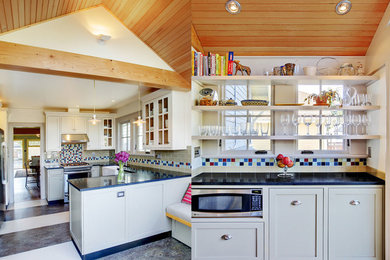 Example of a classic u-shaped linoleum floor open concept kitchen design in Seattle with a farmhouse sink, white cabinets, green backsplash, subway tile backsplash, stainless steel appliances and a peninsula
