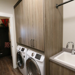 Mittelgroße Industrial Waschküche in L-Form mit Einbauwaschbecken, flächenbündigen Schrankfronten, hellbraunen Holzschränken, Laminat-Arbeitsplatte, grauer Wandfarbe, Vinylboden und Waschmaschine und Trockner nebeneinander in Sonstige