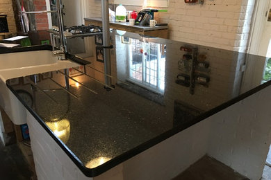 Inspiration for a contemporary kitchen in West Midlands with a belfast sink, granite worktops and an island.