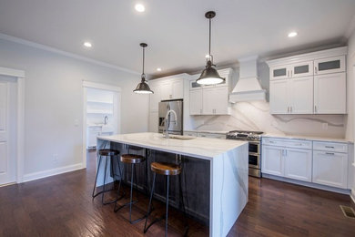 Mid-sized transitional single-wall dark wood floor and brown floor eat-in kitchen photo in New York with an undermount sink, recessed-panel cabinets, white cabinets, quartz countertops, white backsplash, stone slab backsplash, stainless steel appliances and an island