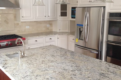 Enclosed kitchen - large contemporary u-shaped medium tone wood floor enclosed kitchen idea in Chicago with a double-bowl sink, raised-panel cabinets, white cabinets, granite countertops, beige backsplash, subway tile backsplash, stainless steel appliances and an island