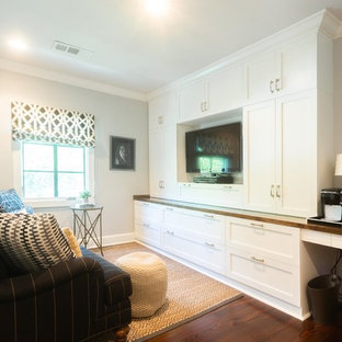Home theater - mid-sized transitional enclosed dark wood floor and brown floor home theater idea in Little Rock with gray walls and a media wall