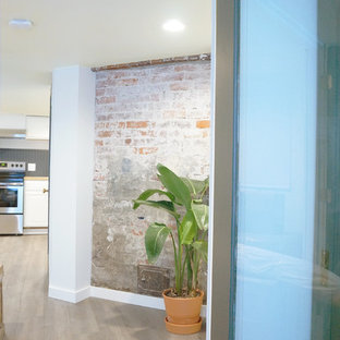 This is an example of a small modern look-out basement in Seattle with white walls, laminate floors, no fireplace, a brick fireplace surround and grey floors.