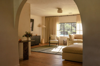 Inredning av ett medelhavsstil stort loftrum, med ett finrum, beige väggar, mellanmörkt trägolv, en väggmonterad TV, flerfärgat golv, en standard öppen spis och en spiselkrans i tegelsten