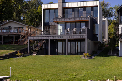 Large minimalist blue three-story concrete fiberboard and board and batten exterior home photo in Minneapolis with a black roof