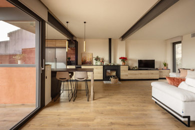 Ejemplo de salón abierto minimalista de tamaño medio con paredes beige, suelo de madera en tonos medios, estufa de leña, marco de chimenea de metal y suelo marrón
