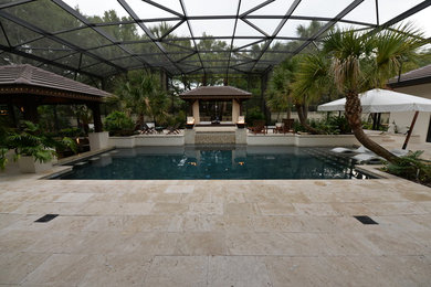 Large country backyard custom-shaped pool in Orlando with natural stone pavers.