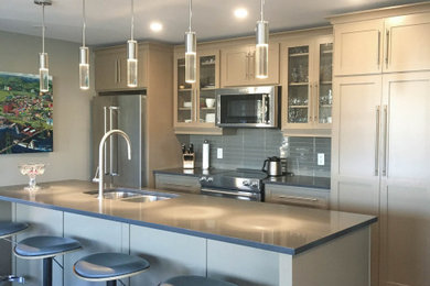 Mid-sized trendy galley slate floor and multicolored floor open concept kitchen photo in Other with an undermount sink, shaker cabinets, gray cabinets, quartz countertops, gray backsplash, glass tile backsplash, stainless steel appliances, an island and black countertops
