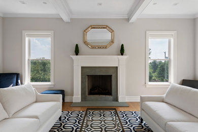 Example of a large farmhouse medium tone wood floor, brown floor and coffered ceiling family room design in Philadelphia with beige walls, a standard fireplace, a plaster fireplace and no tv