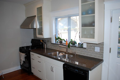 Inspiration for a mid-sized transitional medium tone wood floor kitchen remodel in Toronto with a double-bowl sink, shaker cabinets, white cabinets, beige backsplash, matchstick tile backsplash and black appliances