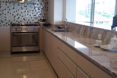 Mid-sized minimalist galley porcelain tile and beige floor open concept kitchen photo in Las Vegas with an undermount sink, flat-panel cabinets, beige cabinets, marble countertops, beige backsplash, glass tile backsplash and stainless steel appliances