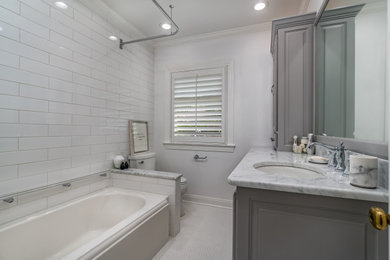 Small elegant white tile and ceramic tile ceramic tile, white floor and single-sink bathroom photo in Other with raised-panel cabinets, gray cabinets, a two-piece toilet, white walls, an undermount sink, marble countertops, white countertops and a built-in vanity