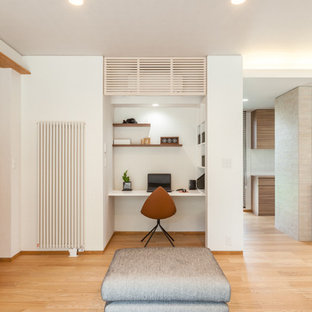 Modern inredning av ett litet arbetsrum, med vita väggar, ljust trägolv, ett inbyggt skrivbord och brunt golv