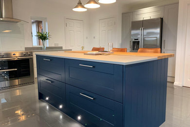 This is an example of a mid-sized modern l-shaped eat-in kitchen in Other with shaker cabinets, blue cabinets, quartzite benchtops, ceramic floors, with island, grey floor and beige benchtop.