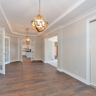 На фото: большая гостиная-столовая в классическом стиле с серыми стенами, полом из винила и коричневым полом с