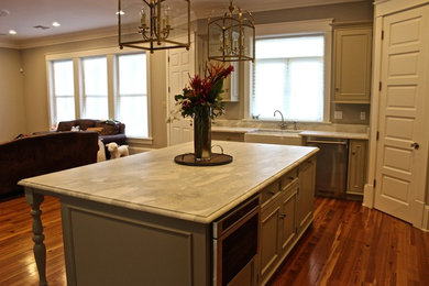 This is an example of a large country kitchen in New Orleans with a farmhouse sink, marble benchtops, white splashback, stone slab splashback, dark hardwood floors and with island.
