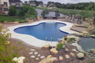 Design ideas for a mid-sized backyard custom-shaped natural pool in Minneapolis with a hot tub.