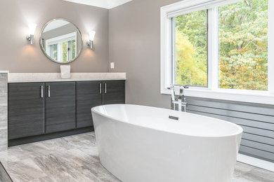 Inspiration for a large contemporary master bathroom in Boston with flat-panel cabinets, dark wood cabinets, a freestanding tub, a curbless shower, a two-piece toilet, gray tile, porcelain tile, grey walls, porcelain floors, an undermount sink, engineered quartz benchtops, grey floor, a hinged shower door and white benchtops.