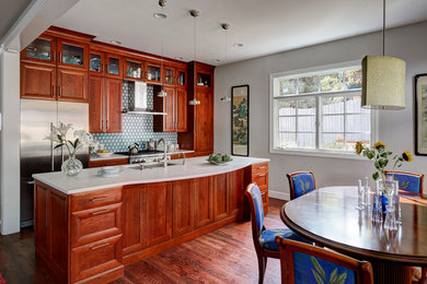 This is an example of a mid-sized contemporary galley eat-in kitchen in Denver with a single-bowl sink, shaker cabinets, medium wood cabinets, solid surface benchtops, multi-coloured splashback, ceramic splashback, stainless steel appliances, medium hardwood floors and with island.