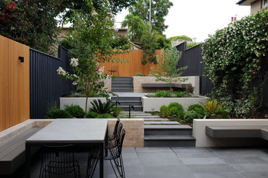 Large contemporary backyard full sun garden in Sydney with natural stone pavers.