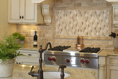 Kitchen - mid-sized traditional single-wall kitchen idea in Phoenix with recessed-panel cabinets, distressed cabinets, granite countertops, beige backsplash, ceramic backsplash, stainless steel appliances, an island and an undermount sink