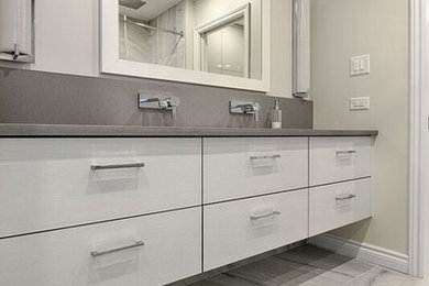 Mid-sized trendy master gray tile and ceramic tile ceramic tile doorless shower photo in Ottawa with flat-panel cabinets, gray cabinets, gray walls, a trough sink and quartz countertops
