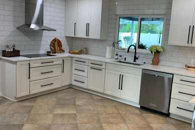 タンパにある広いモダンスタイルのおしゃれなキッチン (ドロップインシンク、シェーカースタイル扉のキャビネット、白いキャビネット、クオーツストーンカウンター、白いキッチンパネル、サブウェイタイルのキッチンパネル、シルバーの調理設備、セラミックタイルの床、アイランドなし、ベージュの床、白いキッチンカウンター) の写真