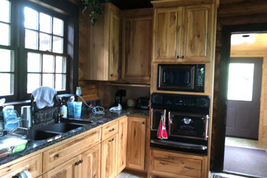 Inspiration for a small rustic u-shaped cement tile floor and beige floor eat-in kitchen remodel in Minneapolis with an undermount sink, raised-panel cabinets, brown cabinets, granite countertops, black backsplash, black appliances, an island and blue countertops