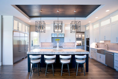 Transitional brown floor kitchen photo in Other with a farmhouse sink, shaker cabinets, white cabinets, metallic backsplash, metal backsplash, stainless steel appliances, an island and gray countertops