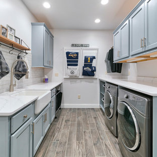 Traditional galley separated utility room in Other with a belfast sink, recessed-panel cabinets, blue cabinets, white walls, a side by side washer and dryer, brown floors and white worktops.