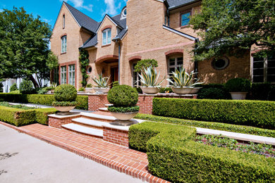 This is an example of a large eclectic two-storey brick red house exterior in Dallas with a hip roof and a tile roof.