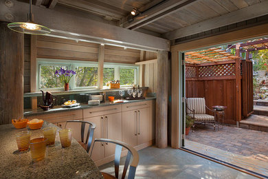Inspiration for a mid-sized transitional porcelain tile eat-in kitchen remodel in San Francisco with light wood cabinets, an island, a farmhouse sink, flat-panel cabinets, glass sheet backsplash, stainless steel appliances and recycled glass countertops
