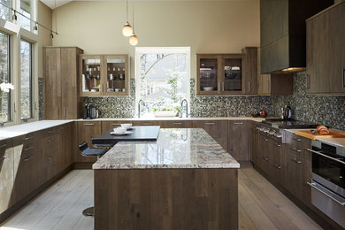 Inspiration for a large contemporary u-shaped kitchen in Detroit with an undermount sink, shaker cabinets, dark wood cabinets, granite benchtops, metallic splashback, glass tile splashback, stainless steel appliances, with island, medium hardwood floors and brown floor.