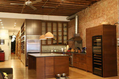 Inspiration for a mid-sized industrial l-shaped light wood floor and beige floor open concept kitchen remodel in New York with an undermount sink, flat-panel cabinets, medium tone wood cabinets, soapstone countertops, metallic backsplash, metal backsplash, stainless steel appliances and an island