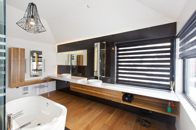 Inspiration for a large modern master black tile and ceramic tile light wood floor and beige floor freestanding bathtub remodel in Montreal with flat-panel cabinets, medium tone wood cabinets, white walls, a vessel sink and solid surface countertops