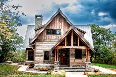Идея дизайна: двухэтажный, деревянный, коричневый частный загородный дом среднего размера в стиле рустика с двускатной крышей, металлической крышей и серой крышей