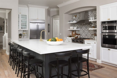 Light wood floor kitchen photo in Sacramento with a farmhouse sink, shaker cabinets, quartzite countertops, multicolored backsplash, cement tile backsplash, stainless steel appliances and an island