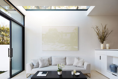 This is an example of a modern open concept living room in Sydney with white walls and white floor.