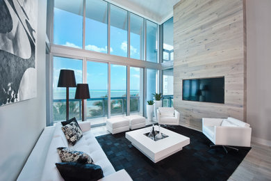 This is an example of a contemporary living room in Miami with grey walls and a wall-mounted tv.
