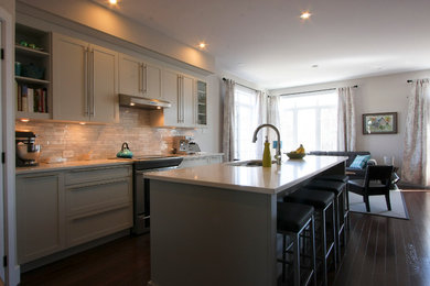 Inspiration for a mid-sized transitional galley dark wood floor kitchen remodel in Ottawa with an undermount sink, shaker cabinets, gray cabinets, quartz countertops, gray backsplash, stone tile backsplash, stainless steel appliances and an island
