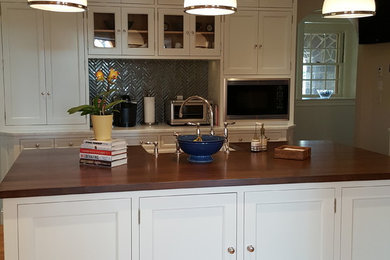 Inspiration for a mid-sized traditional kitchen in Bridgeport with a farmhouse sink, beaded inset cabinets, white cabinets, wood benchtops, blue splashback, ceramic splashback, stainless steel appliances, light hardwood floors and with island.