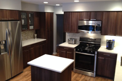 Photo of a mid-sized contemporary separate kitchen in Chicago with an undermount sink, flat-panel cabinets, dark wood cabinets, quartz benchtops, white splashback, stone tile splashback, stainless steel appliances, light hardwood floors and with island.