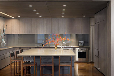 Large minimalist u-shaped dark wood floor and brown floor open concept kitchen photo in New York with a double-bowl sink, flat-panel cabinets, gray cabinets, solid surface countertops, gray backsplash, glass sheet backsplash, paneled appliances and an island