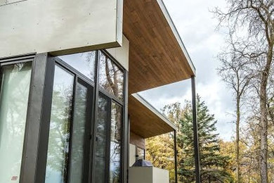 Large modern beige one-story concrete house exterior idea in Other with a shed roof