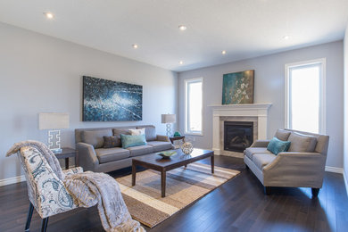 Inspiration for a mid-sized timeless formal and enclosed dark wood floor and brown floor living room remodel in Toronto with gray walls, a standard fireplace, a stone fireplace and no tv