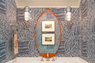 Example of a small trendy powder room design in Other with recessed-panel cabinets, white cabinets, blue walls, an undermount sink, solid surface countertops and white countertops