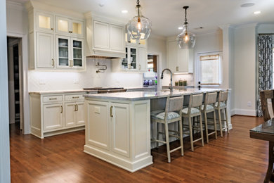 Large transitional medium tone wood floor and brown floor eat-in kitchen photo in Atlanta with a farmhouse sink, beaded inset cabinets, beige cabinets, quartzite countertops, white backsplash, ceramic backsplash, stainless steel appliances, an island and beige countertops
