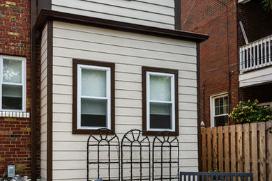 This is an example of a small transitional one-storey yellow house exterior in St Louis with mixed siding.