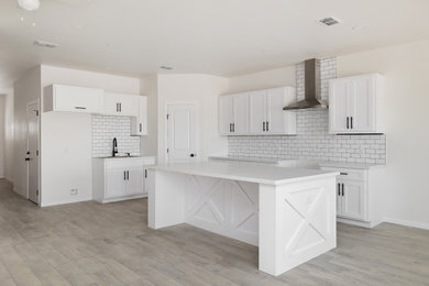 Inspiration for a small country single-wall kitchen pantry remodel in Austin with a double-bowl sink, raised-panel cabinets, white cabinets, quartzite countertops, white backsplash, ceramic backsplash, black appliances, an island and white countertops